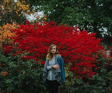 woman standing behind red flowers thumbnail
