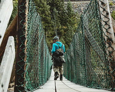 man in blue hoodie walking on hanging bridge thumbnail
