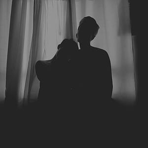 silhouette photo of two person standing in front of window curtain thumbnail