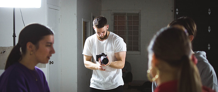man in white shirt holding DSLR camera thumbnail