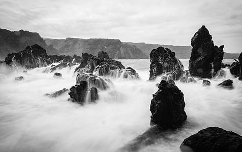time lapse and grayscale photography of wave of water on rocks thumbnail