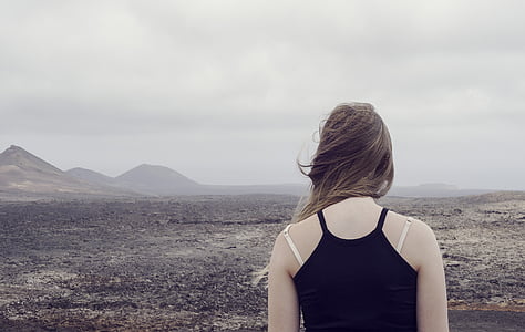 woman wearing black camisole top facing deserted land thumbnail