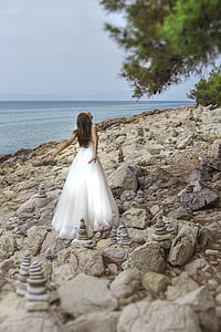 woman wearing white sleeveless gown near body of water during daytime thumbnail