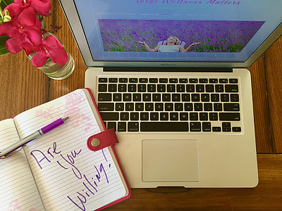 MacBook Air beside binder with purple pen thumbnail