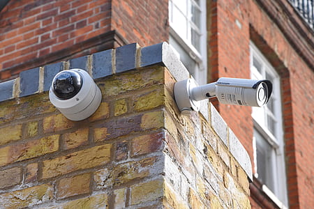 two white assorted-type wall mounted security cameras on brown brick wall thumbnail