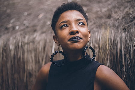 woman wearing black sleeveless top and beaded black earrings looking up at daytime thumbnail