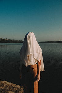 woman wearing white headdress near a body of water thumbnail