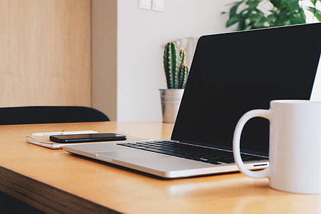 close up photo of white ceramic mug, MacBook Pro and black android smartphone thumbnail