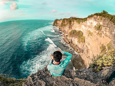 Man Wearing Blue Long Sleeve Top On Top Of Mountain Near Body Of Water thumbnail