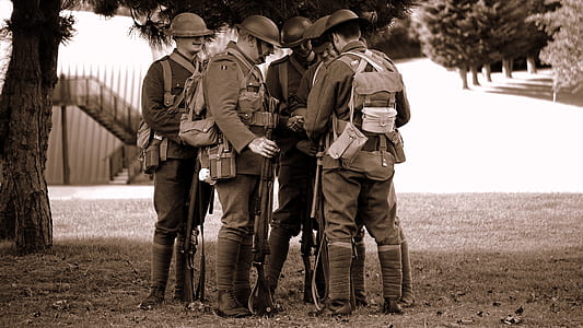 grayscale photo of soldier standing near tree thumbnail