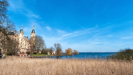 white and brown concrete building beside body of water under blue sky at daytime thumbnail