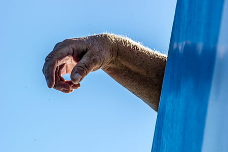 photo of human hand under blue sky thumbnail