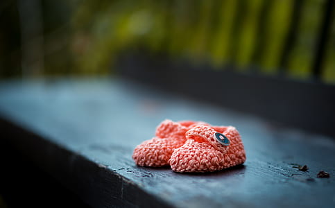 shallow focus photography of pair of toddler's pink patik knitted shoes on black wooden board during daytime thumbnail