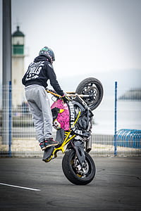 person doing trick on black and yellow motorcycle thumbnail