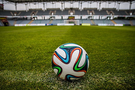 tilt-shift lens photography of multicolored soccer ball on green grass soccer field of an empty stadium thumbnail