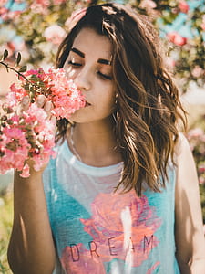 woman smelling pink petaled flowers thumbnail