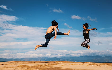 two people jumping near body of water thumbnail