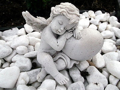 white cherub statue on white rocks thumbnail