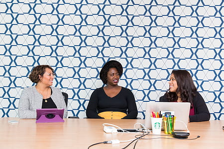 Three Women Sitting in Front of a Wooden Table thumbnail