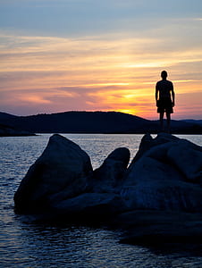 man standing on rock formation during sunset thumbnail