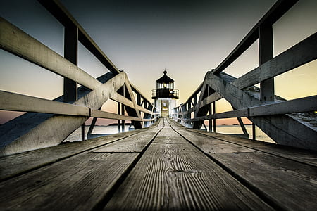 wooden dock leading towards lighthouse at daytime thumbnail