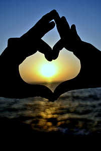 silhouette of two hands forming heart behind sunset thumbnail