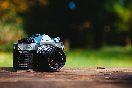 selective focus photography of gray and black Canon SLR camera on brown ground thumbnail