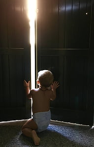 baby kneeling on the ground trying to open the door thumbnail