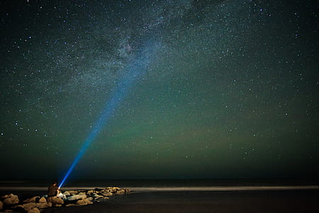 person sitting on rock holding flashlight during nighttime thumbnail