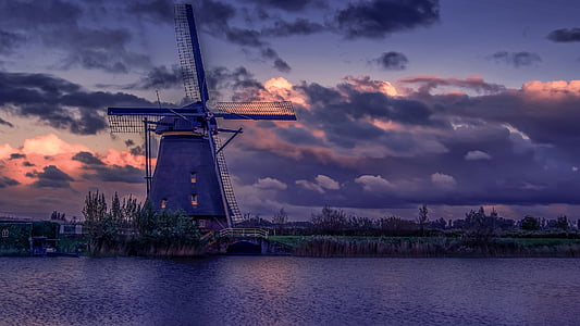 windmill near body of water under cloudy sky thumbnail