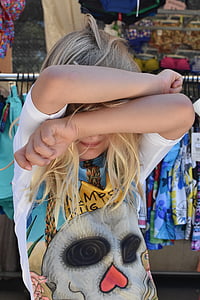 girl wearing white and multicolored t-shirt covering face with her arms thumbnail