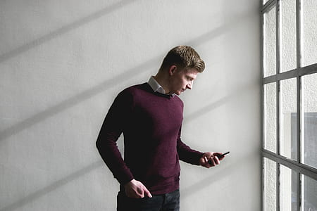 man holding smartphone near window thumbnail