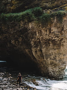 woman standing in front of cliff during daytime thumbnail