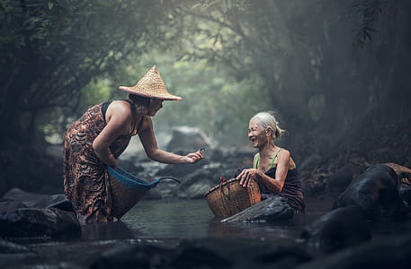 two women on body of water near green leaf trees during daytime thumbnail