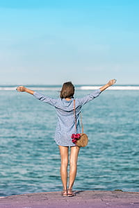woman raising her hands beside body of water thumbnail
