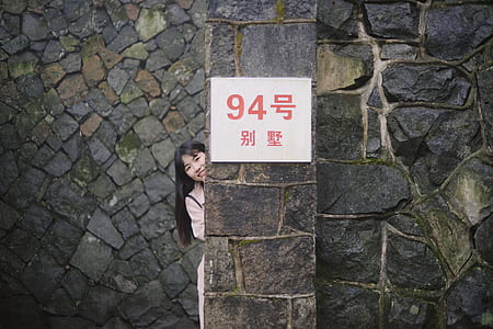 girl standing behind gray wall thumbnail