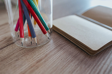 Notebooks with colourful pencils on a wooden desk thumbnail