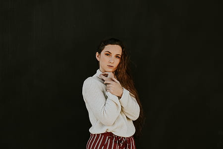 woman in white sweater standing on black background thumbnail