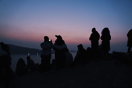silhouette of people standing and sitting on hill thumbnail