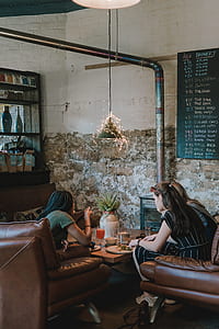 three women sitting on couch beside table inside white room thumbnail