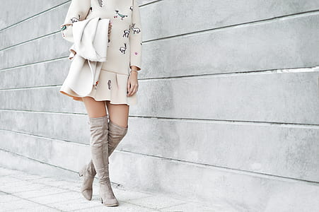woman standing besides gray concrete wall while holding white coat thumbnail