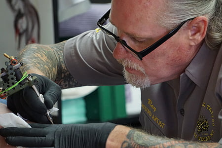 man doing tattoo inside building thumbnail