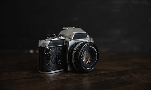 black and silver DSLR camera on brown wooden surface thumbnail