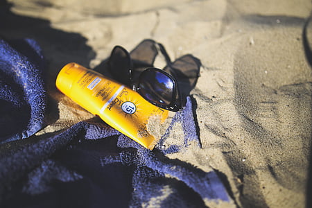 sunglasses and sunblock lotion on sand thumbnail