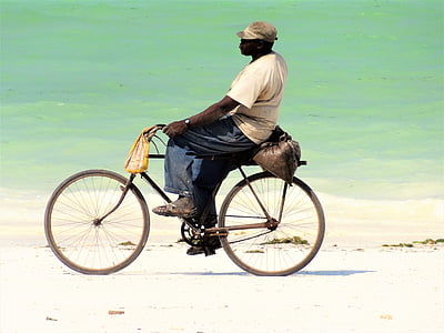 man in beige shirt and blue pants riding bike on shoreline thumbnail