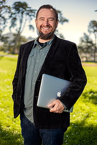man in black coat holding silver MacBook thumbnail
