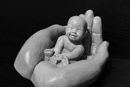 grayscale photo of baby on person's hand figurine thumbnail