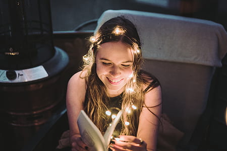 woman reading book with string lights wrap around her head thumbnail