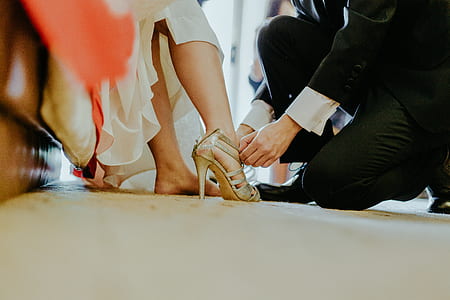 man kneeling while fixing woman's sandal inside room thumbnail