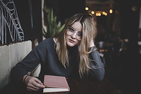 selective focus photography of woman in gray sweater sitting in front of table inside room thumbnail